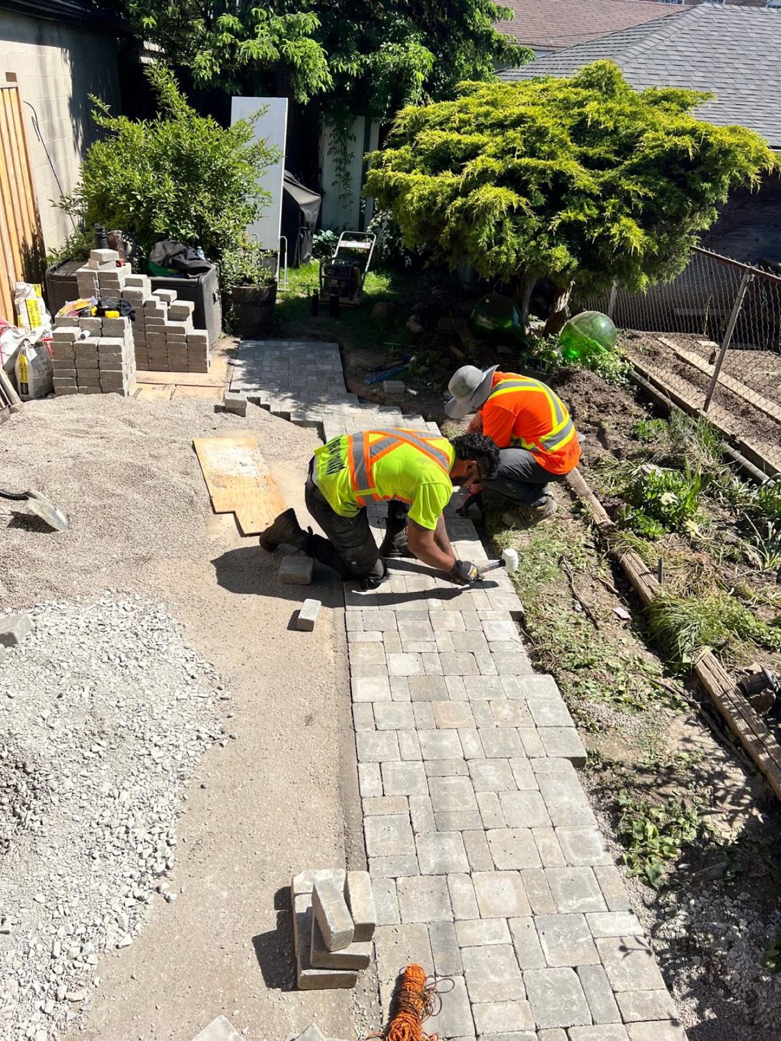 Crew laying interlock pavers by hand